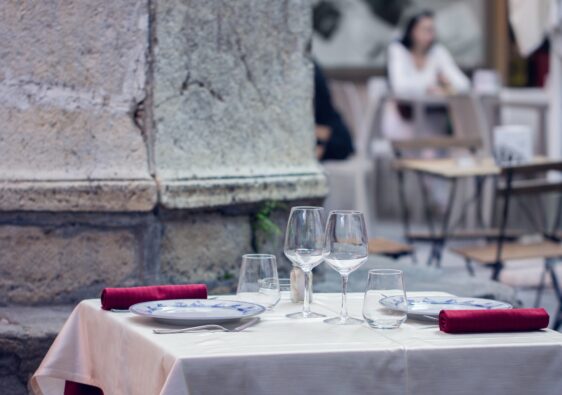 Empty outdoor restaurant table for two. Summer terrace of café. Blurred background.