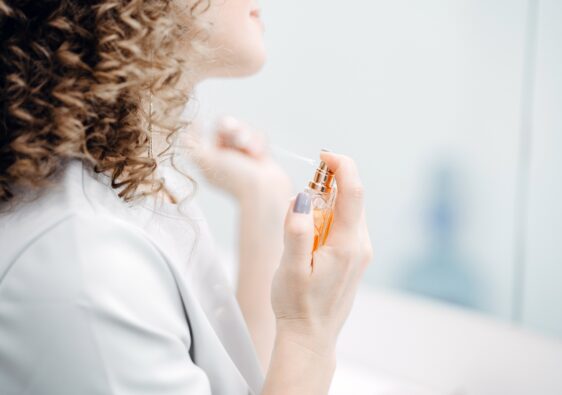 A woman with curly hair sprinkles perfume.