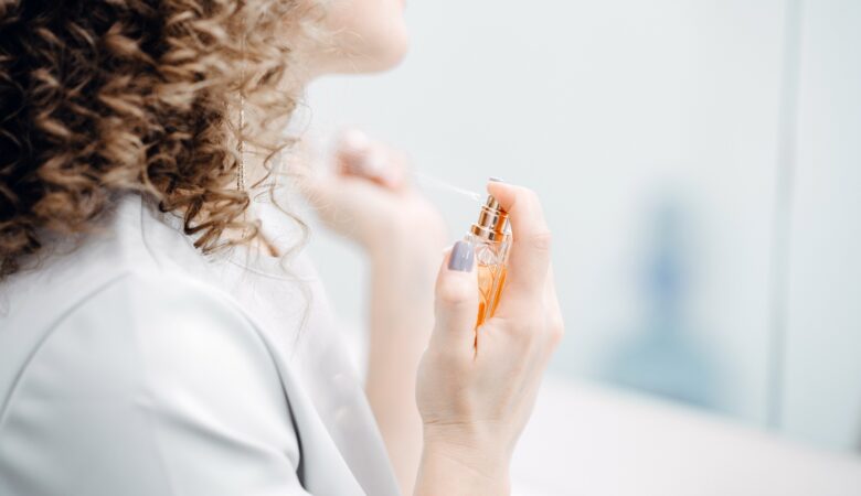 A woman with curly hair sprinkles perfume.