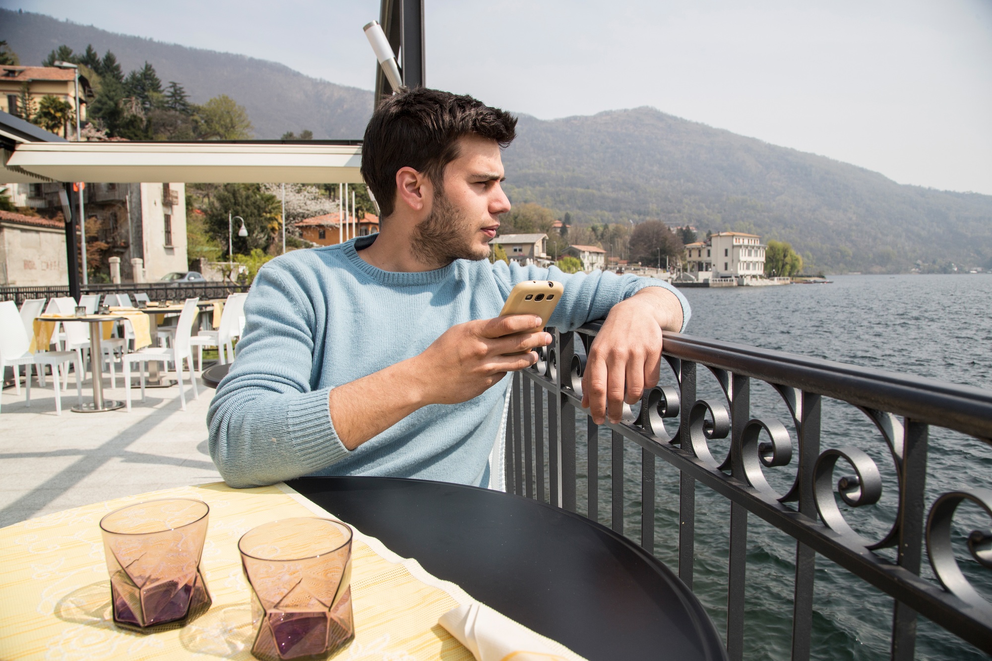 Young man looking out from lakeside restaurant, Lake Mergozzo, Verbania, Piemonte, Italy